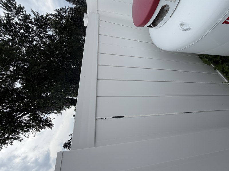 A vertical separation opening between fence panel boards near the top rail.