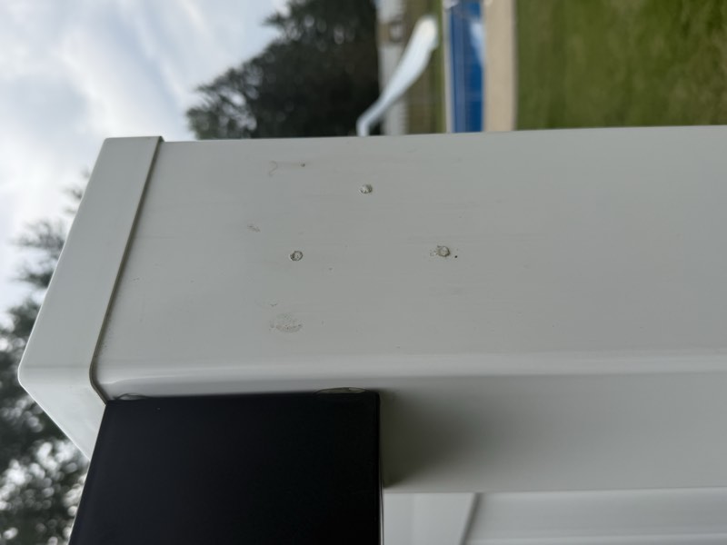Several caulk plugs covering abandoned fastener holes on a white fence post.