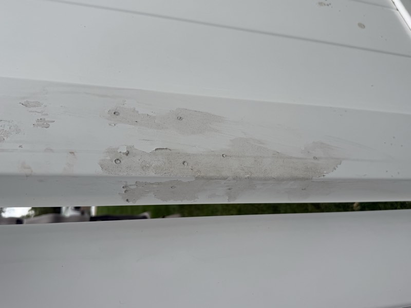 A heavy vertical smear of caulk down the corner of a fence post covering several fastener holes.